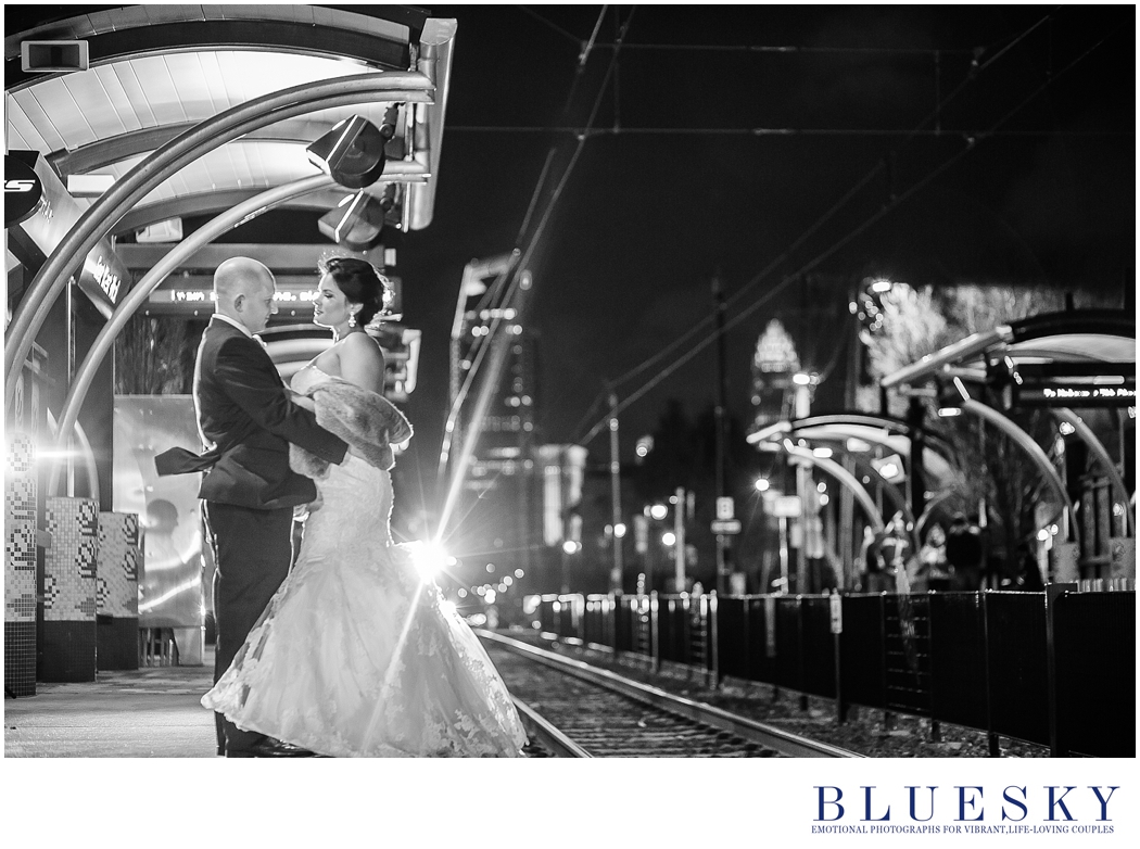 glam uptown image of bride and groom on subway platform in back and white back lit by train