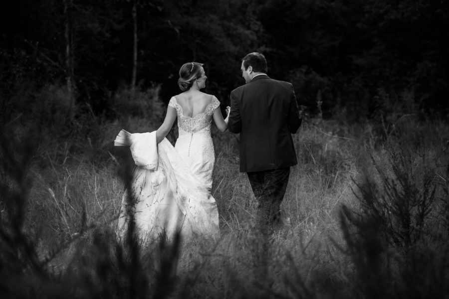 black and white photo of bride and groom in field 
