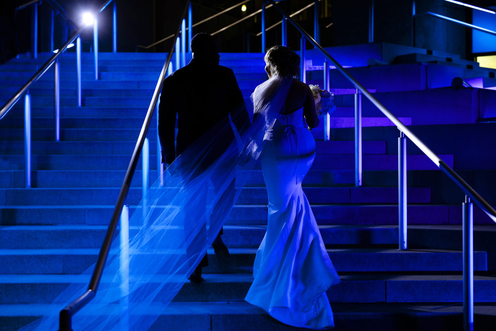 Romantic Night Portrait of a bride and groom going up the The Mint Museum Uptown Steps in Charlotte NC. Blue Uplights