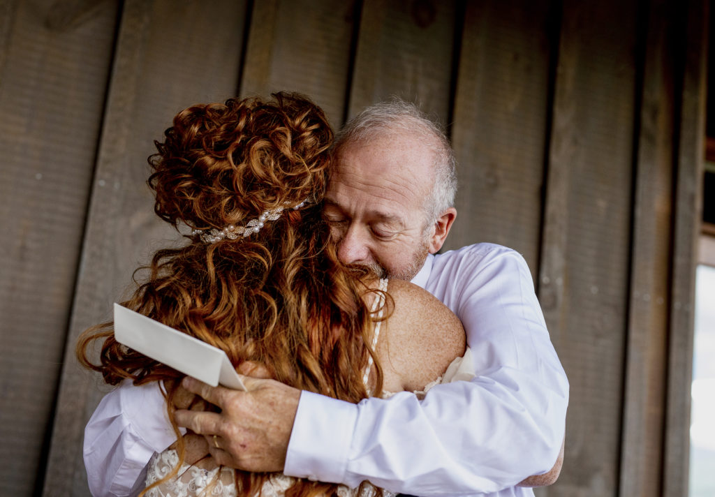 Father cries and hugs his daughter after she gives him a heartfelt letter on her wedding day. moment