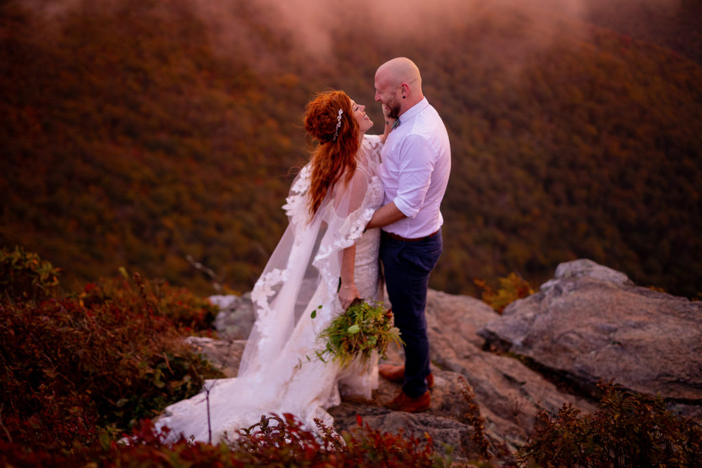 Creative couple portraits in the blue ridge parkway, asheville, nc. Couple hikes Craggy Gardens in their wedding attire for epic sunset portraits.