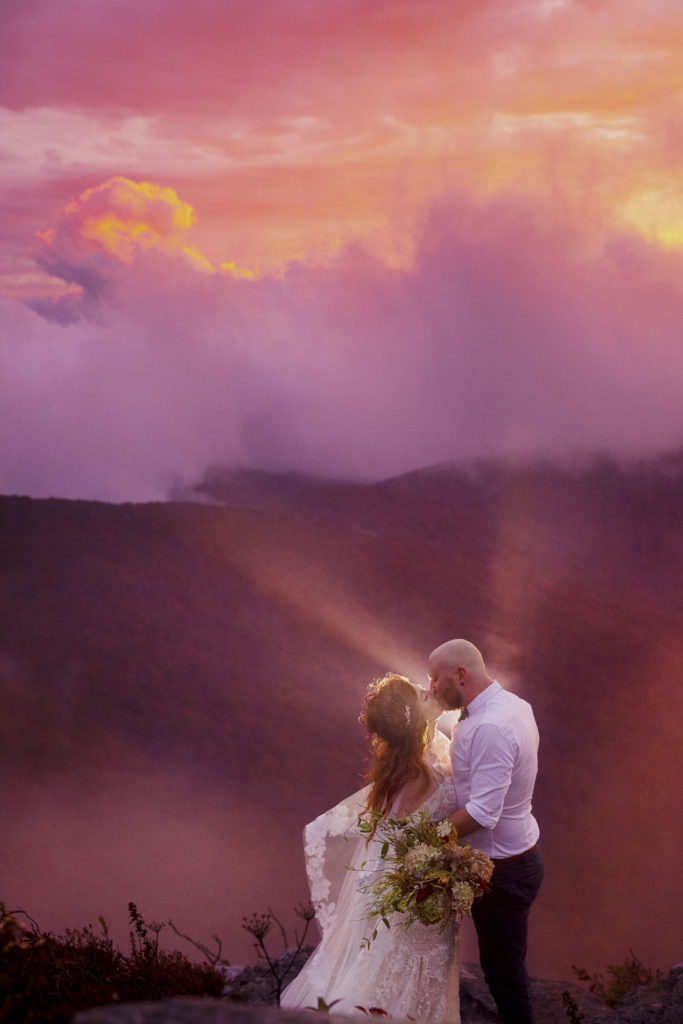 Creative couple portraits in the blue ridge parkway, asheville, nc. Couple hikes Craggy Gardens in their wedding attire for epic sunset portraits.