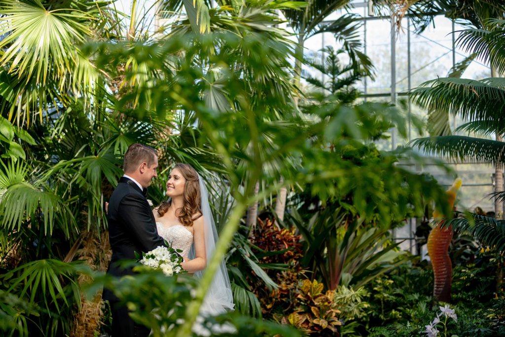 bride and groom on their wedding day. Daniel Stowe Botanical Gardens in the Orchid Conservatory. Greenhouse and garden weddings